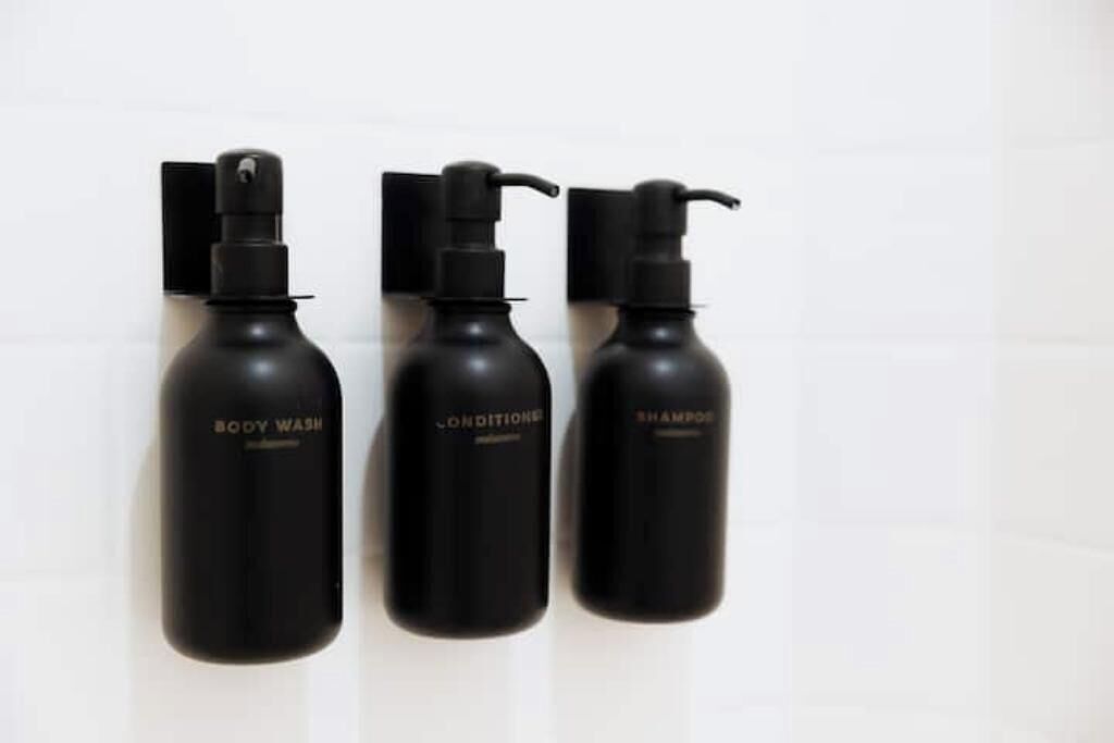 Three black bottles labeled body wash, conditioner, and shampoo.
