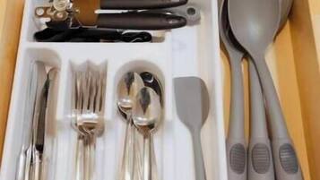 Un cajón con cubiertos, incluyendo tenedores, cucharas y un cuchillo, ordenados en una bandeja blanca.