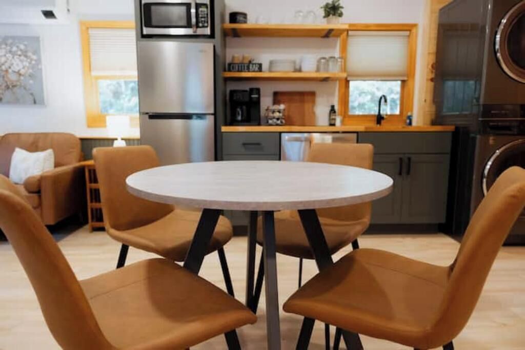 A modern kitchen with a round dining table and four brown chairs.