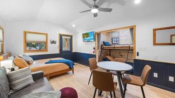 Une pièce comprenant un lit, un canapé, une table à manger avec des chaises, un ventilateur de plafond et une fenêtre donnant sur l’extérieur.