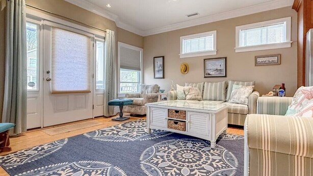A spacious living room with a ceiling fan, a large window, and a patterned rug.