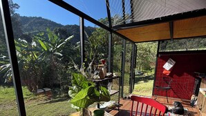 A breakfast table with a view of a lush garden and mountains. - Araucaria Cabin: Design and Nature (Itajubá)