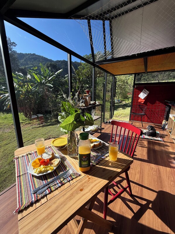 Une table de petit-déjeuner offrant une vue sur un jardin luxuriant et des montagnes.