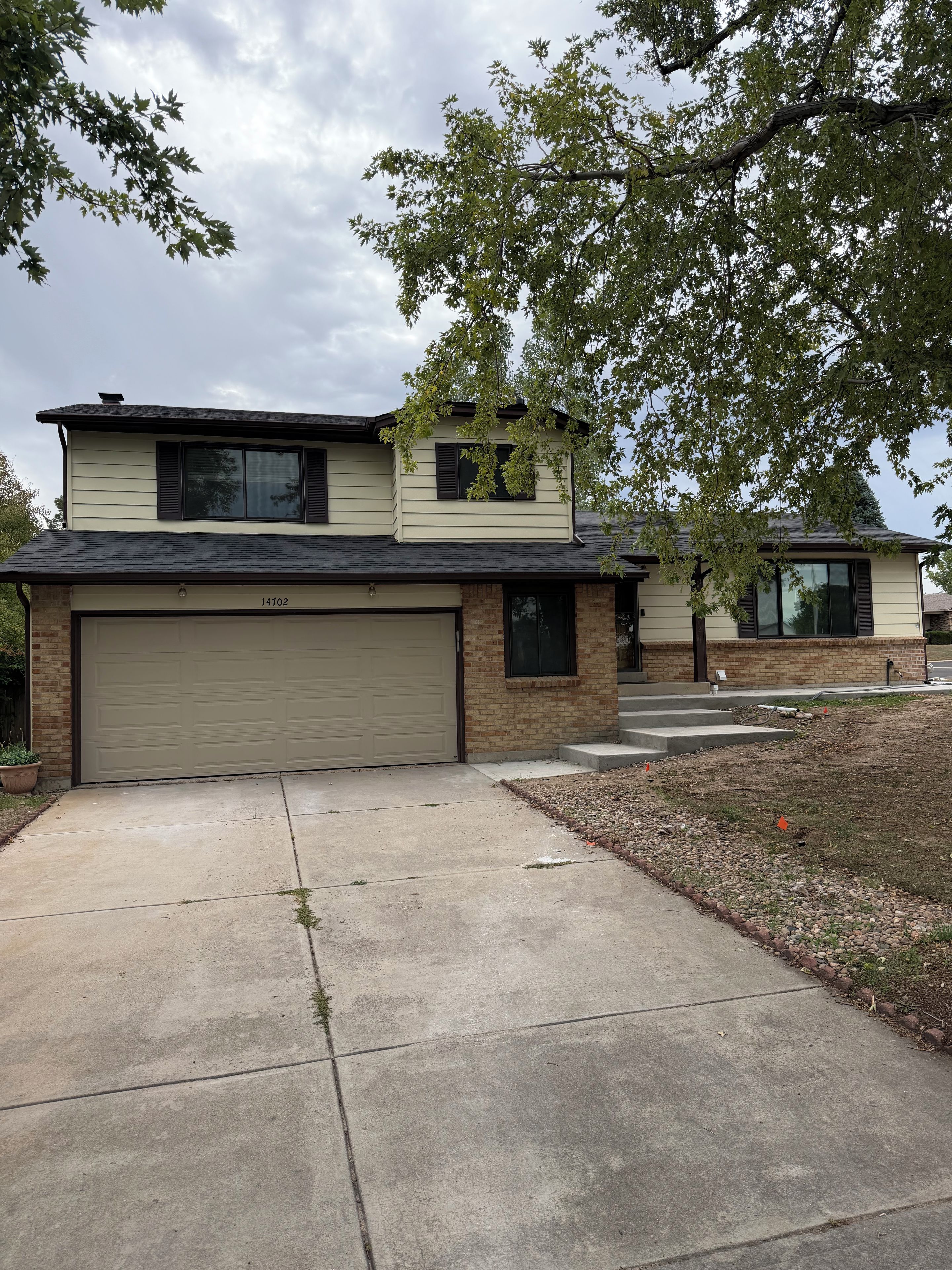 A two-story house with a garage, a brick exterior, and a driveway.