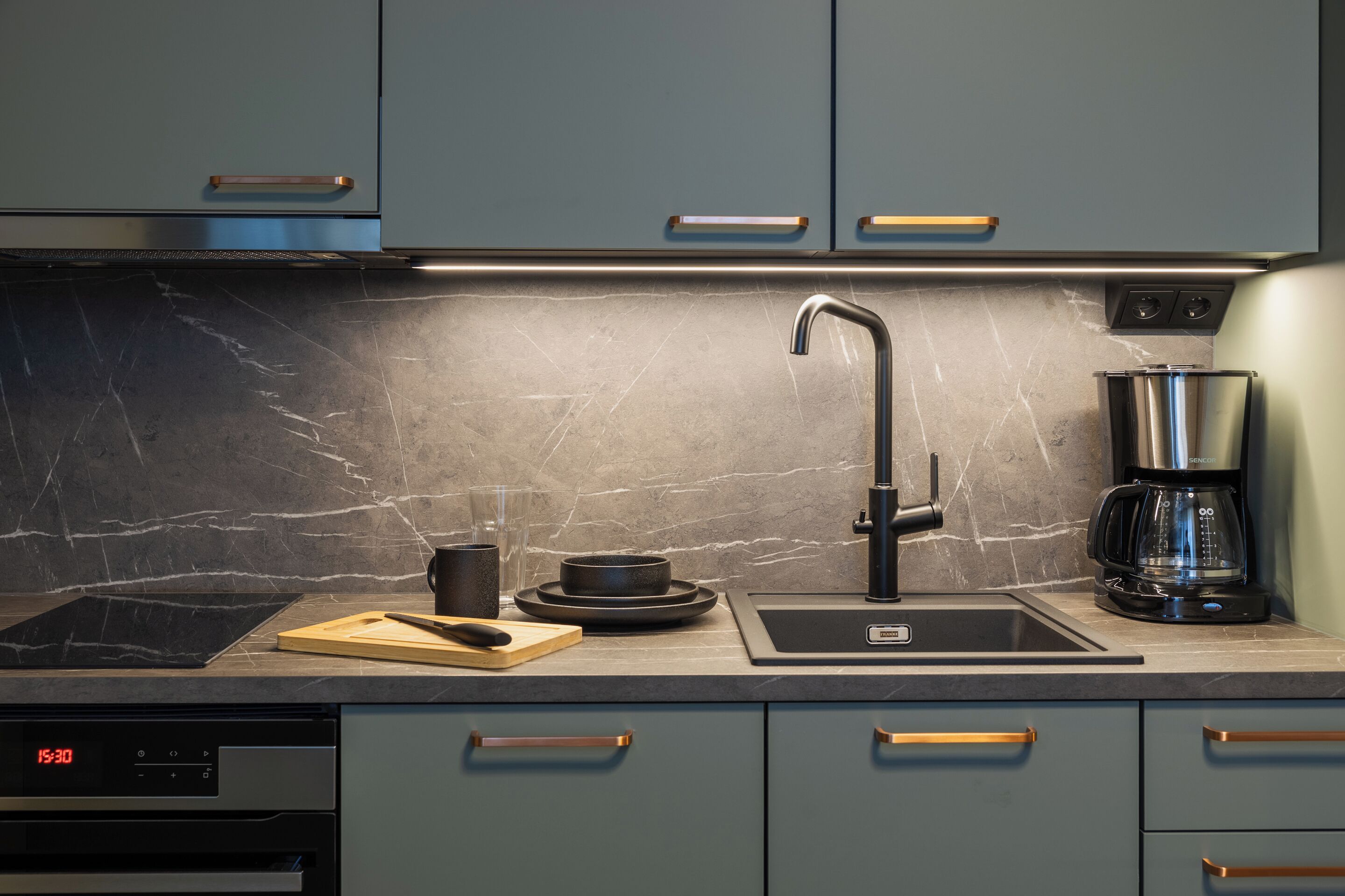A modern kitchen with a built-in dishwasher, a coffee maker, and a sleek faucet.