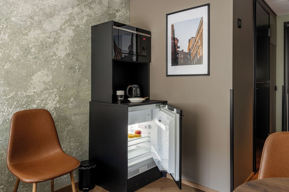 A compact kitchenette with a refrigerator, a coffee maker, and a bowl on the counter.