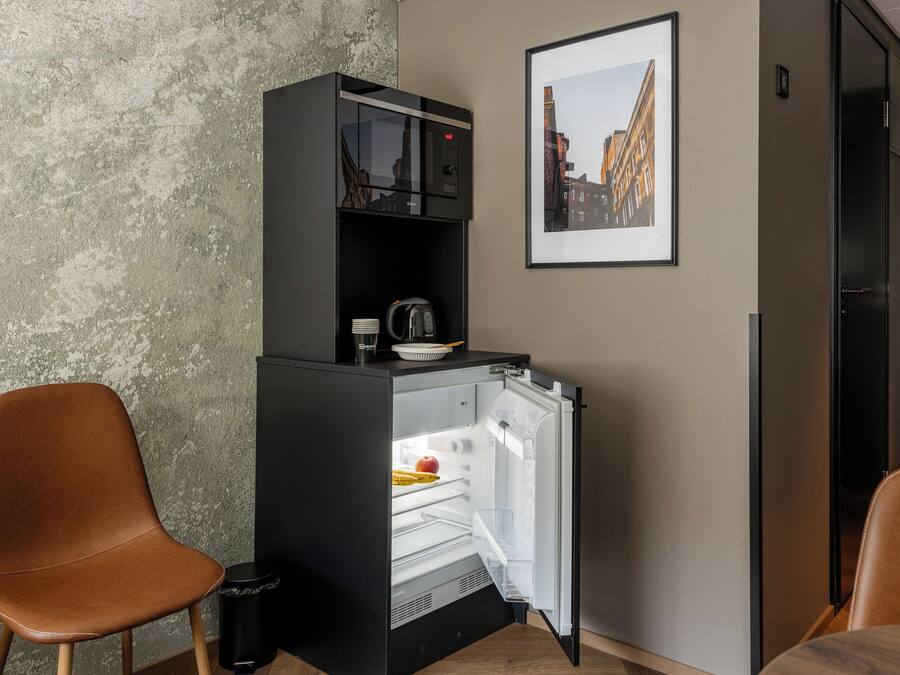 Ett litet, praktiskt kök med ett kylskåp, en kaffebryggare och en skål på bänkskivan.