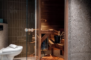 A modern bathroom with a glass shower enclosure, a wooden bench, and a toilet. - Hotel H28 (Tampere)