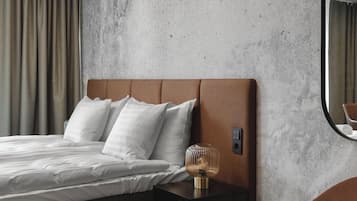Una habitación de hotel con cama, mesita de noche, lámpara y espejo.
