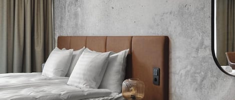 Una habitación de hotel con cama, mesita de noche, lámpara y espejo.