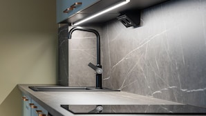 A modern kitchen with a sleek faucet, a countertop, and a backsplash with a marble-like pattern. - Hotel H28 (Tampere)