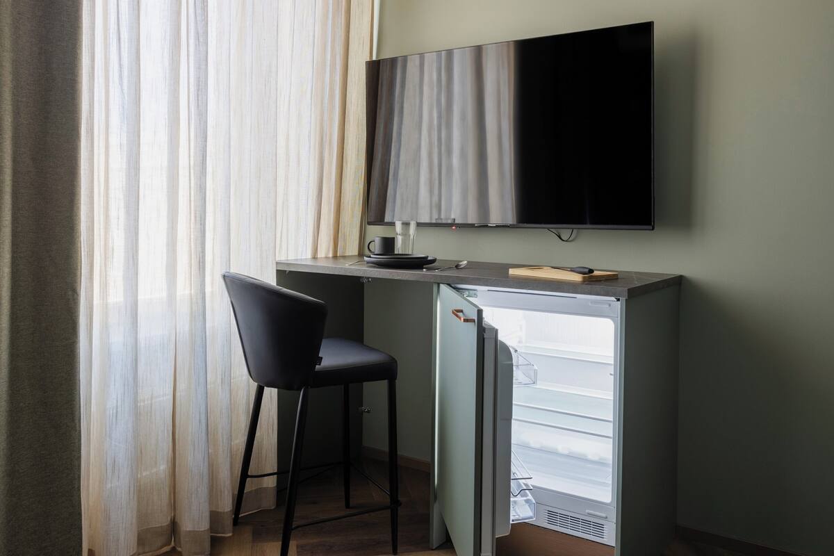 A compact room with a desk, chair, and a small refrigerator.