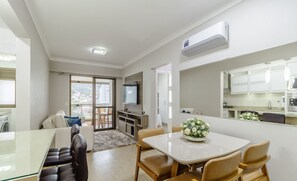 Ein modernes Wohnzimmer mit einem Glastisch, Ledersesseln, einer Couch und einem Fernseher.