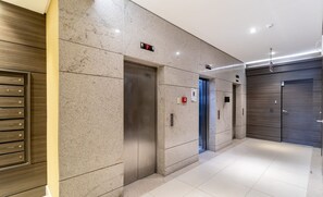 A modern elevator area with a digital display, emergency buttons, and a wall-mounted directory. - PZD - Modern Apartments Near Ufsc (Florianópolis)