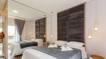 A modern hotel room with two beds, a large padded headboard, and pendant lighting.