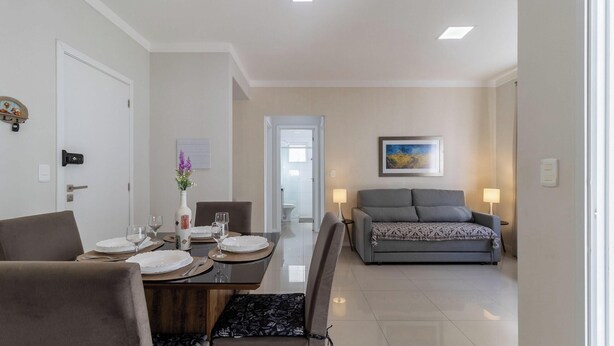A modern living room with a sofa, a dining table set for two, and a bed in the background. - 2 Bedroooms Apt w/ BBQ 500m From the Beach Pts0101 (Florianópolis)