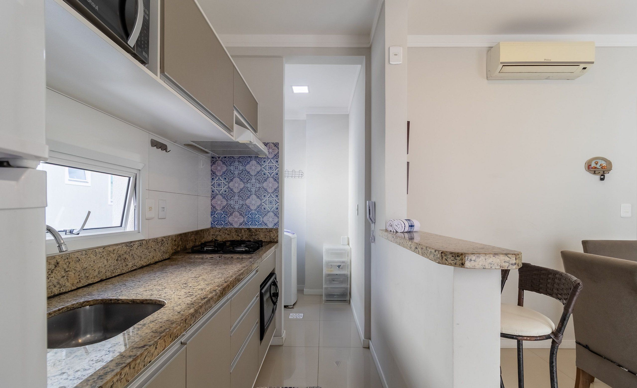 A compact kitchen with a granite countertop, a built-in sink, and a window above the sink.