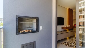 A modern kitchen with a built-in oven, a flat-screen TV, and a wooden cabinet. - Charming Apartment 210m From Jurere Beach Psj0304 (Florianópolis)