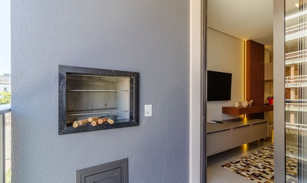A modern kitchen with a built-in oven, a flat-screen TV, and a wooden cabinet. - Charming Apartment 210m From Jurere Beach Psj0304 (Florianópolis)