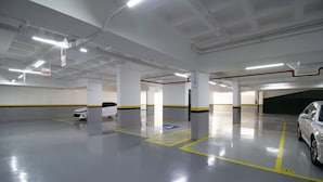 A spacious parking garage with clear markings for parking spaces and a fire extinguisher visible. - Balcony With sea View 230m From the Beach! Prb0405 (Florianópolis)