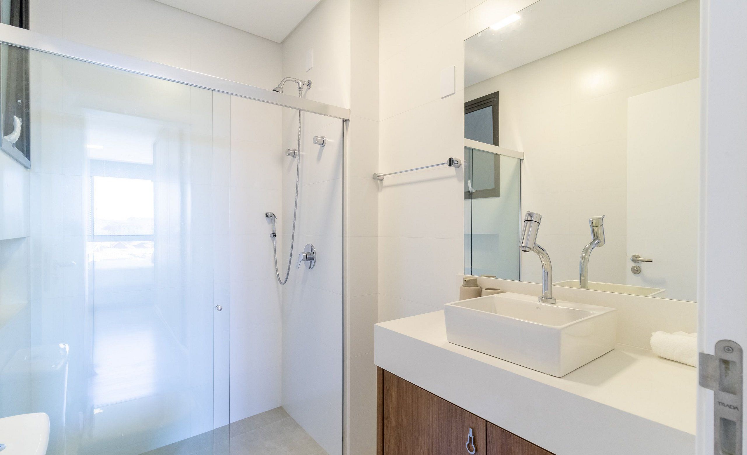 A modern bathroom with a glass shower enclosure, a white sink, and a large mirror.