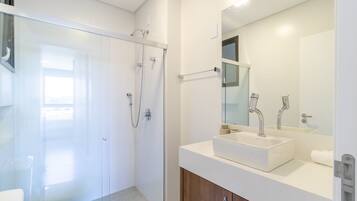 A modern bathroom with a glass shower enclosure, a white sink, and a large mirror.