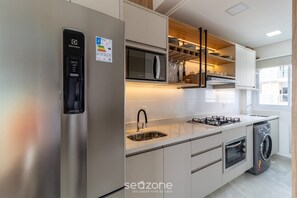 A modern kitchen with a stainless steel refrigerator, a built-in microwave, a gas stove, a sink, and a built-in oven. - Nice and Equipped Apt. 200m From the Beach Pra0304 (Florianópolis)