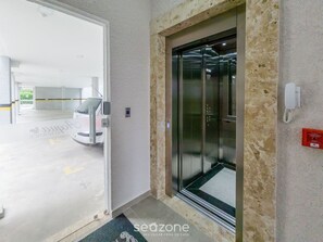 An elevator with a glass door, a parking garage entrance, and a security intercom system.