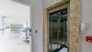 Een lift met glazen deur, een parkeergarage-ingang en een beveiligingsintercomsysteem.