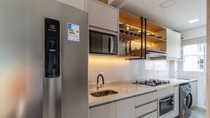Een moderne keuken met een roestvrijstalen koelkast, een inbouwmagnetron, een gasfornuis, een spoelbak en een inbouwoven.