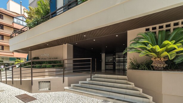 A hotel entrance with a modern design, featuring a staircase leading to the entrance, a metal railing, and a potted plant. - Apartment w/ Barbecue 450m From the Beach Pnm0202 (Florianópolis)