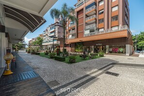 A modern building with multiple balconies, a central courtyard with plants, and a storefront with a visible sign. - Apartment w/ Barbecue 450m From the Beach Pnm0202 (Florianópolis)
