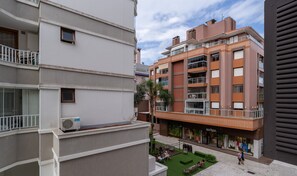 Ein mehrgeschossiges Wohngebäude mit Balkonen, einer Dachterrasse und einem Gewerbebereich im Erdgeschoss.