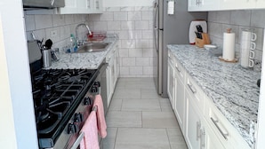 A modern kitchen with white cabinets, a stainless steel stove, a microwave, and a refrigerator. - Columbia University 3Bedroom 1 1/2 Bath Across Cathedral of St. John the Divine (New York)