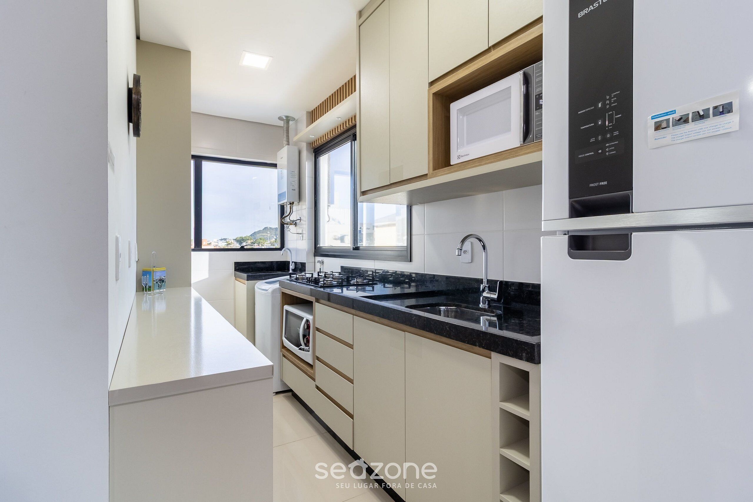A modern kitchen with a built-in microwave, stainless steel appliances, and a window providing natural light.
