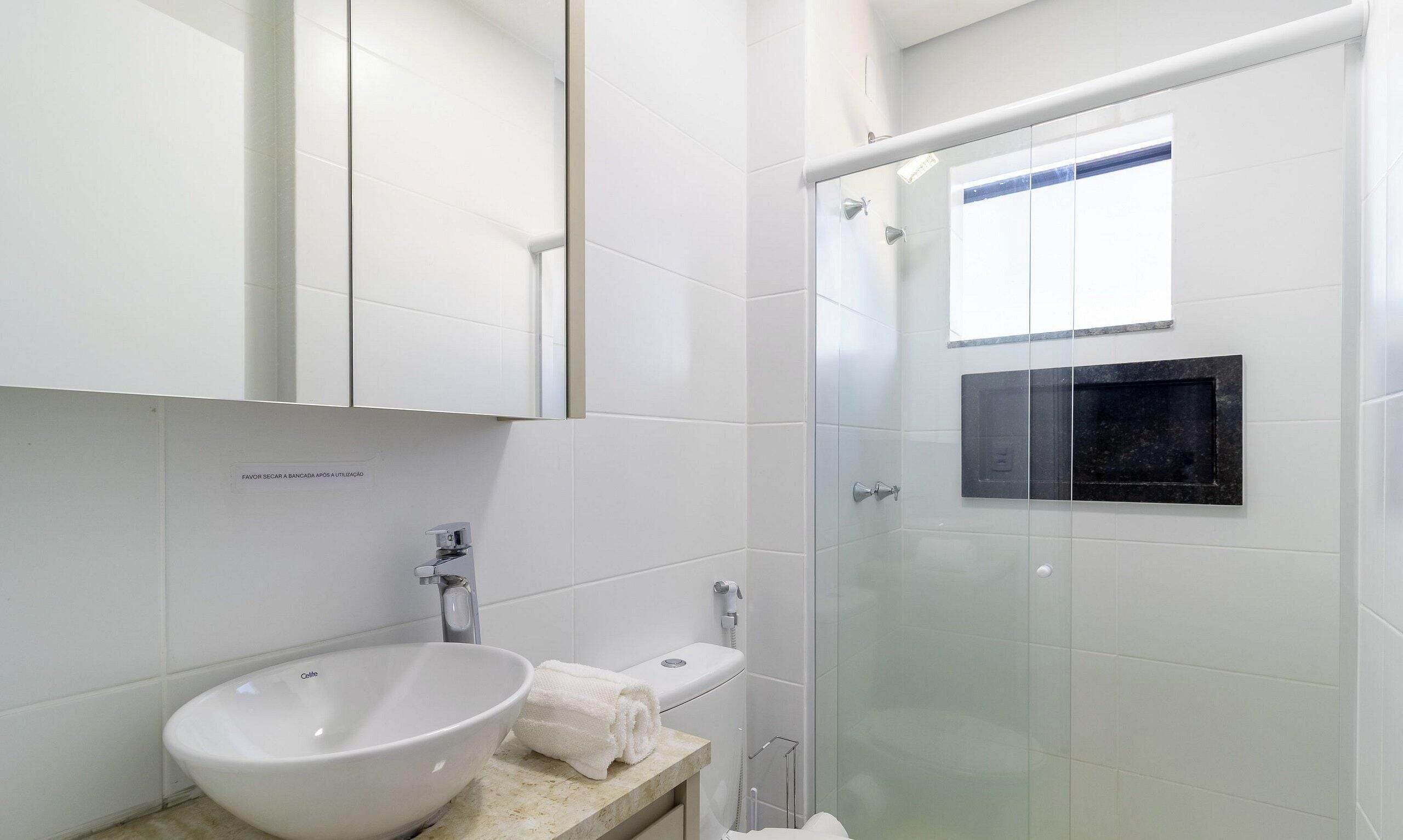 Une salle de bain moderne avec une douche à parois de verre, un lavabo blanc et des toilettes.