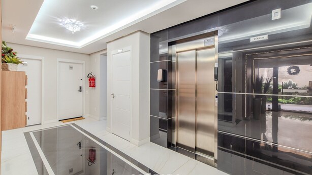 A modern hotel lobby with a glass floor, a reception desk, a fire extinguisher, and an elevator. - Charming Studio Just 200m From the Beach - Pmo0404 (Florianópolis)