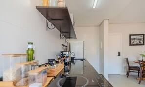 Cozinha moderna com fogão embutido, geladeira e diversos utensílios de cozinha.