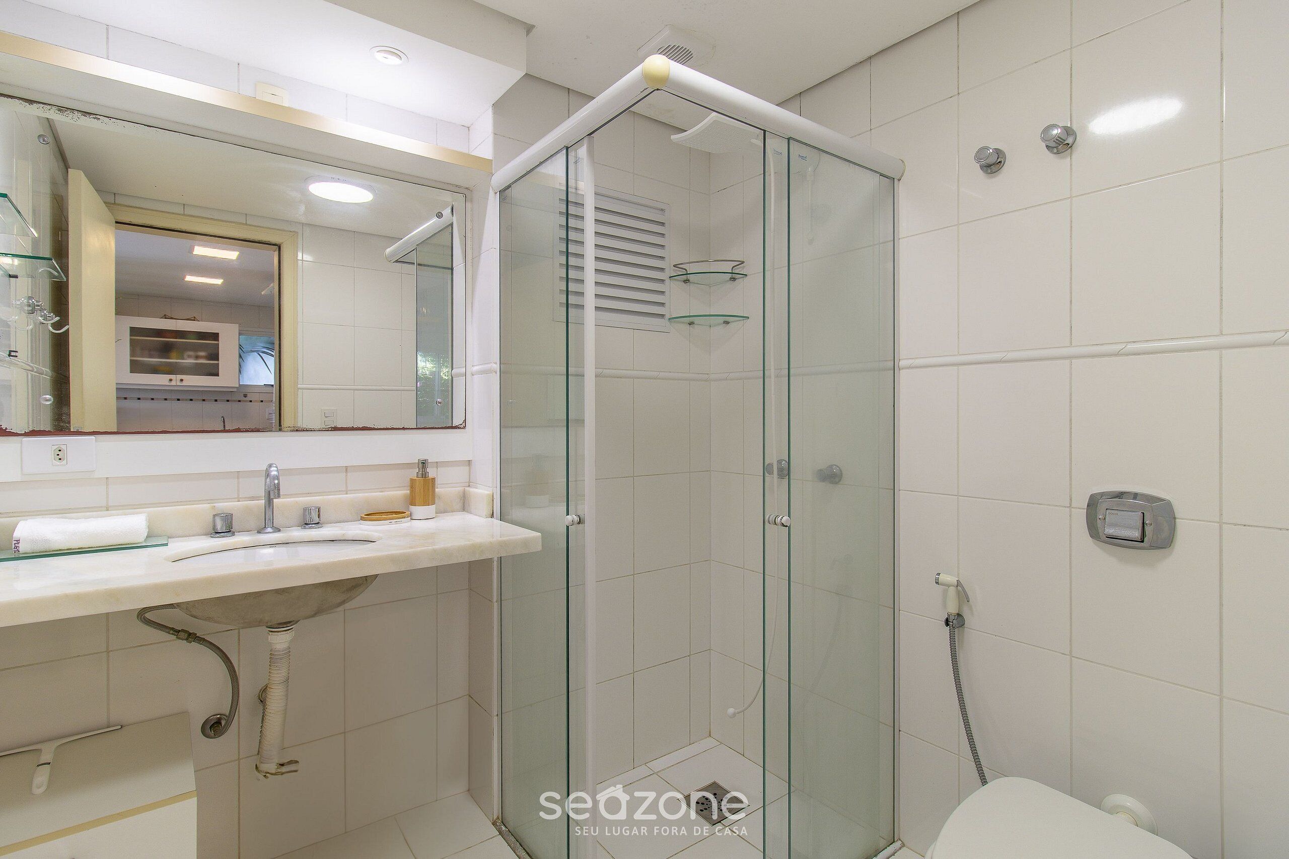 A modern bathroom with a glass-enclosed shower, a white sink, and a toilet.