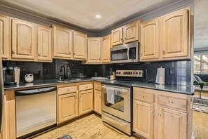 Una cocina con armarios de madera, electrodomésticos de acero inoxidable y una encimera negra.