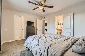 Un dormitorio con cama, ventilador de techo, cómoda y televisor.