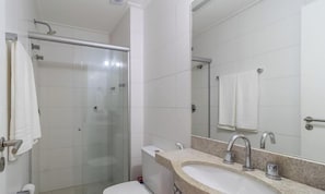 Casa de banho com cabine de duche em vidro, sanita, lavatório com espelho e um porta-toalhas.