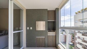 Un baño moderno con un revestimiento de azulejos, un mueble de tocador de madera, un espejo y una ventana con vistas a la ciudad.
