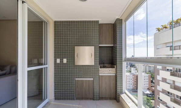 A modern bathroom with a tiled backsplash, a wooden vanity, a mirror, and a window overlooking a cityscape.