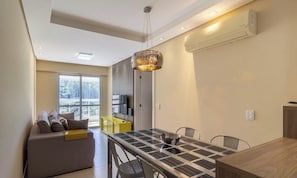 Uma sala de estar moderna com sofá, mesa de jantar e uma janela grande.