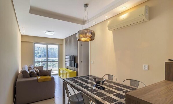 Una sala de estar moderna con un sofá, una mesa de comedor y un ventanal grande.