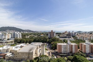 Paisagem urbana com edifícios residenciais, um estacionamento e uma colina ao fundo.