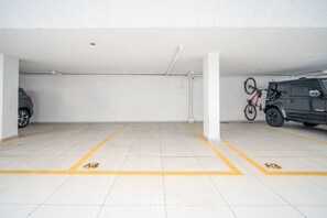 A parking garage with white walls and tiled floors, marked parking spaces A4 and A3, and a bicycle mounted on a wall. - Apt Floripa, 50m to the Beach - Pad0103 (Florianópolis)