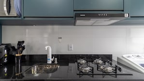 Una cocina con estufa a gas, microondas y lavamanos.