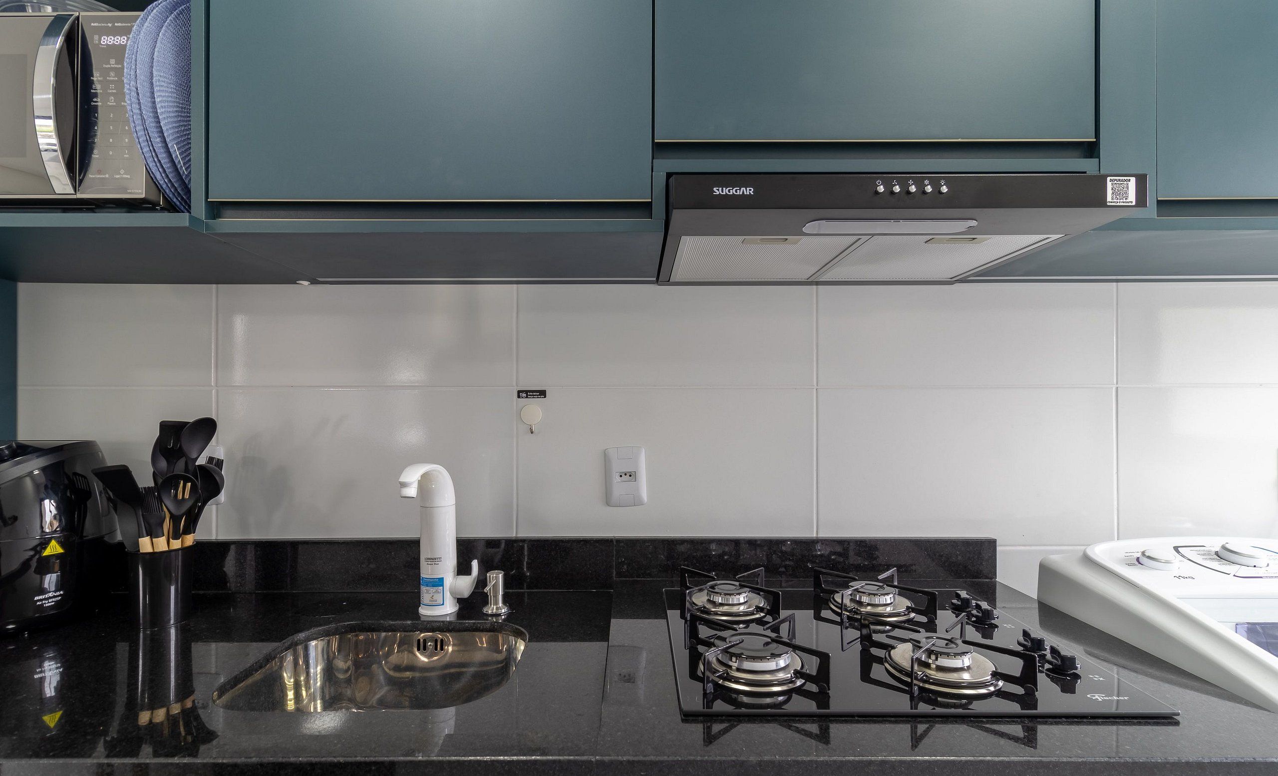 Una cocina con estufa a gas, microondas y lavamanos.